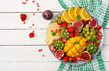 Naklejka na ściany i meble Platter fruits and berries. Mango, kiwi, fig, strawberry, grapes, pear and orange. Vegan cuisine. Dietary menu. Flat lay. Top view