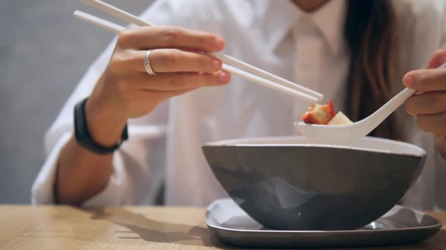 Asian Tourist Girl Eating with Chopsticks Traditional Tom Yam Noodle Soup in Restaurant. 4K.