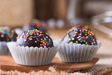 Colorful Chocolate Sprinkles on Tasty Round Chocolate Coated Cakes