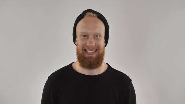 portrait smiling hipster man looking at the camera with cheerful laughing. handsome guy with beard and red hair wearing in black cap. attractive millennial men in casual clothes