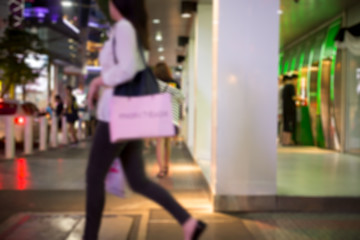 Blurred concept woman walking with shopping bag in city in motion blur