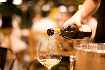 Shot in high iso with low light man pouring wine from the bottle into a glass