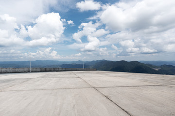 empty concrete floor with green hill in cloud sky