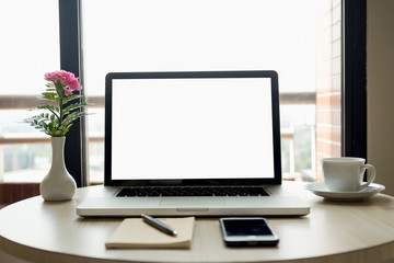 Blank laptop screen with flowers and cell phone and coffee and pen