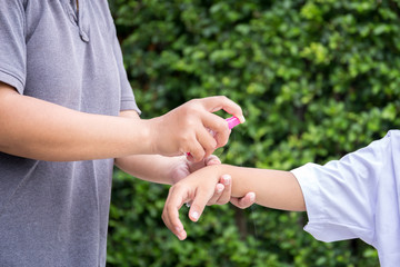 Mother spraying insect repellents on her son arm