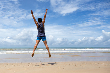 Happy man jumping at the beach in blue sky
