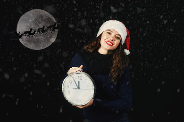 young woman holding a clock indicating the time of Christmas .