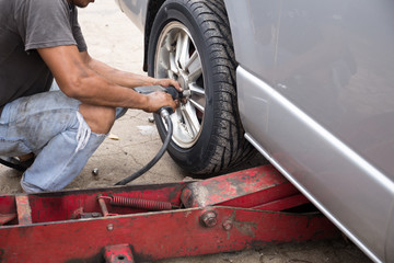 Mechanic changing car wheel with  ipneumatic wrench