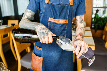 Portrait of a waiter pouring champagne into a flute