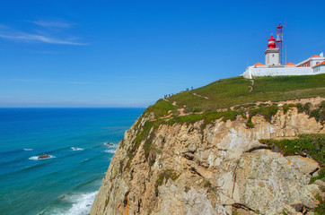 Fototapeta na wymiar The red lighthouse in Cabo da Roca Cape Roca , the westernmost point of Portugal and continental Europe, where the land ends and the sea begins . Beautiful landscape background near Sintra.