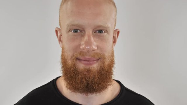 Close up portrait handsome man with beard and red hair. Happy hipster guy looking at the camera closeup face. Millennial persone in studio.