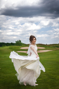 Attractive bride dancing and smiling on green golf course