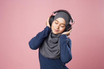Young woman enjoying the music and relax with sport outfit on pink background.