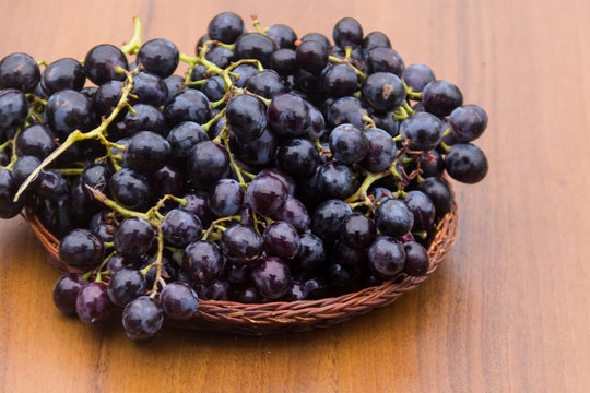 Ripe grapes in wicker basket on wooden table