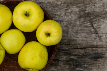 Ripe green apples in a basket on rustic wooden table
