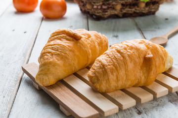 Tasty croissants on white wood background