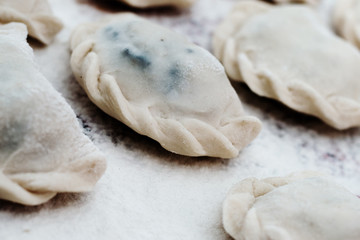 Vareniki (dumplings) with potatoes on white background - traditional Ukrainian and Russian food. Cooking raw dumplings with potatoes. Ravioli