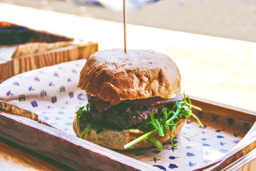 Tasty burger on wooden board of restorant in vintage style
