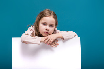 Pretty, little girl in sweater with brunet hair hold clean paper