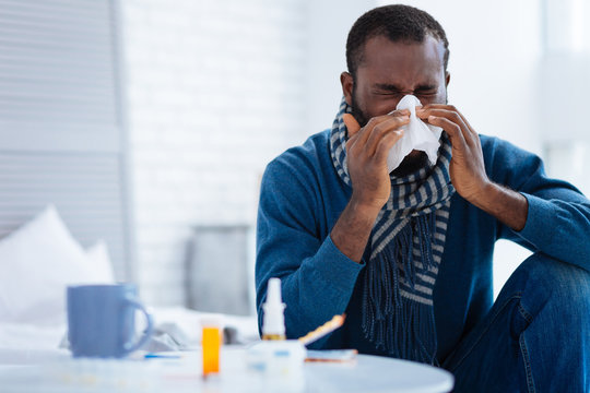 Pleasant Young Man Sitting And Sneezing