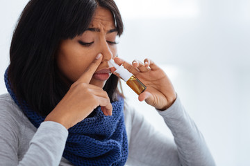 Concentrated unhappy woman using nasal drops