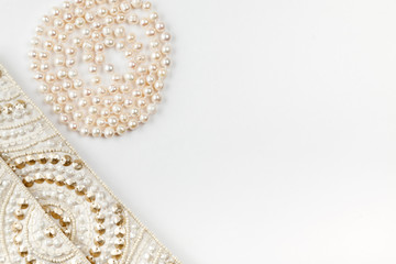 Female white bag and pearl necklace on a white background top view