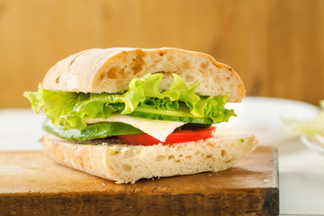 Vegetarian sandwich with avocado, tomato, egg and green salad on a wooden board