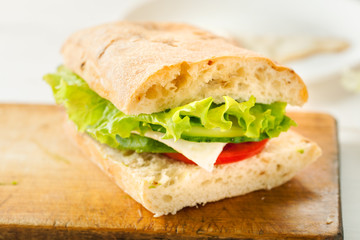 Vegetarian sandwich with avocado, tomato, egg and green salad on a wooden board