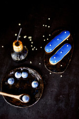 Blue eclairs and candy in blue colors. On a dark background. Pastry arts