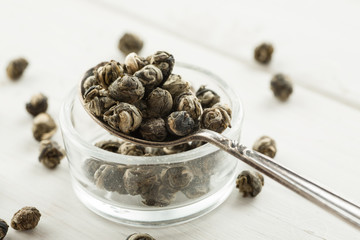 Dry tea balls in a small glass dish with metal spoon