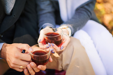 A loving couple is sitting together and drinking tea. A man and a woman are holding a cup. Lovers in the nature in the autumn on a picnic. Autumn picnic with pumpkins apples, tea, samovar, bagels