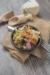 Fresh vegetables and bacon salad in a black bowl. A healthy iceberg salad with olives served on a...
