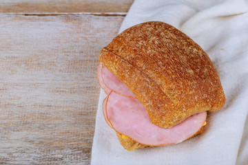 Delicious sandwich stacked high with a juicy ham on wooden table