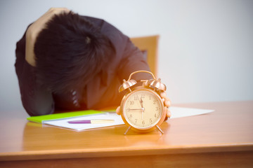 Alarm clock with Businessman Exhausted and sleeping in office on the table, tired and strain about work