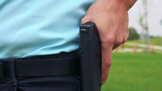 A police officer rests his hand on the gun in the holster - closeup