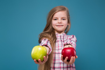 Fototapeta na wymiar Little beauty girl in shirt with long brown hair with apple in hands