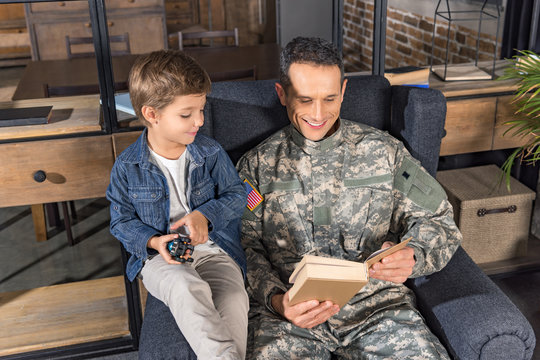 military father and son reading book - Powered by Adobe