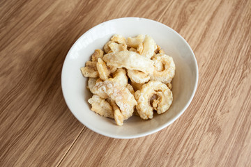 Fried pork rince or Crispy pork skin in white bowl on the wood table, North Thailand food cook from prok skin to fried