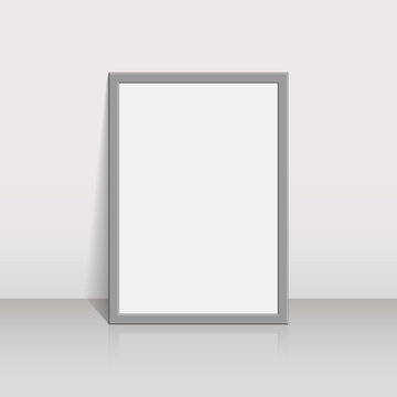 Picture frame on a white wall 3d background design for your content. Blank white paper poster in grey frame standing on a floor. Mock-up template for your design.