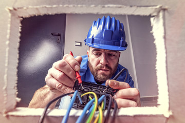  wide angle image, view from inside a wall socket of an electrician who connects cables to an electrical outlet.