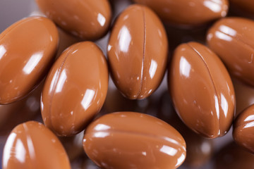 a scattering of brown capsules, tablets on a mirrored background