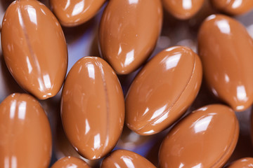 a scattering of brown capsules, tablets on a mirrored background