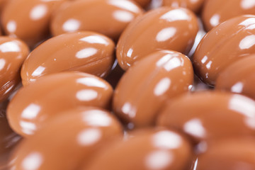 a scattering of brown capsules, tablets on a mirrored background