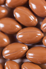 a scattering of brown capsules, tablets on a mirrored background