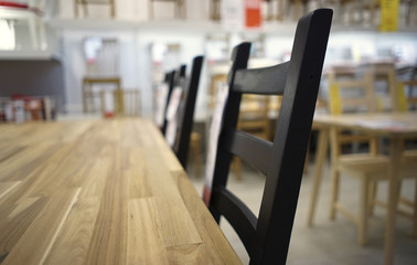 Close-up. Wooden table and black wooden chair in the supermarket. Blurred Background