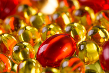 yellow and red medical capsules on a mirror surface