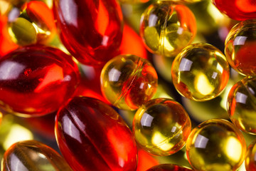yellow and red medical capsules on a mirror surface