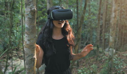 beautiful young brunette woman uses virtual reality glasses in the jungle