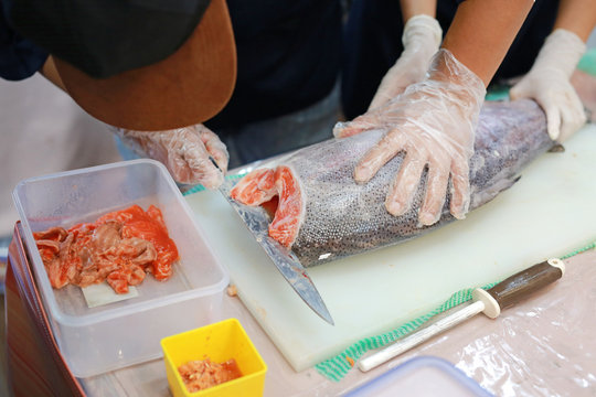 Chef cuts the salmon on a cutting board.
