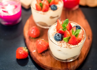Homemade italian dessert tiramisu with strawberries, mint and blueberry in glass